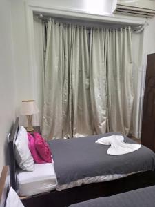 a bed in a bedroom with a window with curtains at Downtown Inn in Cairo