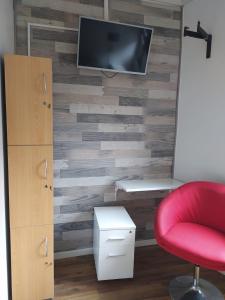 Habitación con silla roja y TV en la pared. en Hostal del Viajero, en Valparaíso