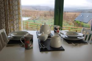 een tafel met borden en keukengerei op een tafel met een raam bij Glas Beag in Spean Bridge