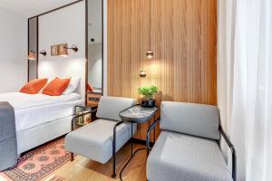 a bedroom with a bed and two chairs and a table at Dom & House - Apartments Granaria in Gdańsk