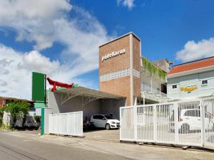 a building with a white fence next to a parking lot at Super OYO 90730 Padekosan in Tulungagung