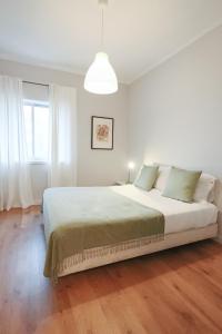 a white bedroom with a large bed and a window at HM – Vilar Apartment in Porto