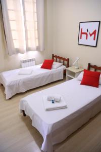 2 Betten mit roten Kissen in einem Zimmer in der Unterkunft Hotel Murialdo in Caxias do Sul