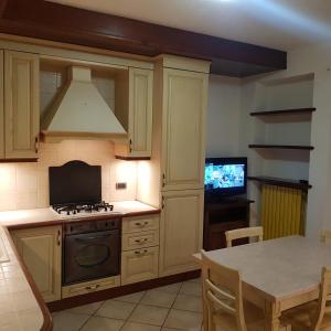 eine Küche mit einem Herd, einem Tisch und einem TV in der Unterkunft Via Sacco in Aosta