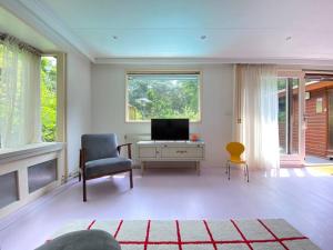 een woonkamer met een tv en een stoel bij Kleurrijk huisje voor 5-personen op de Veluwe in Harderwijk
