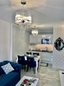 Il comprend un salon avec un canapé bleu et une cuisine. dans l'établissement Apartament Rysy ApartamentyZakopianskie Basen Sauna Jacuzzi, à Zakopane