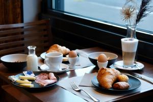 - une table en bois avec des œufs, des croissants et du pain dans l'établissement Hôtel Oasis, à Moutier