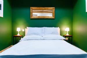 Dormitorio verde con cama blanca y espejo en Monreal Boutique Townhouse - R024RM5 en Paola