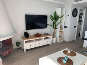 sala de estar con TV de pantalla plana en la pared en Formentor, en Castelldefels