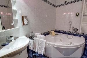 un bagno bianco con vasca e lavandino di Leading Relax Hotel Maria a Moena