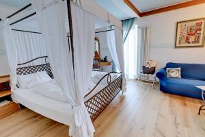 a bedroom with a canopy bed and a blue couch at Leading Relax Hotel Maria in Moena