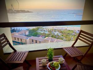 a balcony with two chairs and a table with a plate of fruit at Luxury Casa - Supreme Sea View Apartment JBR Beach 1BR in Dubai