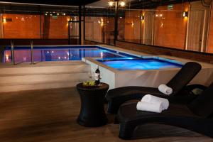 a swimming pool with two chairs and a table at Hotel Brök San Juan del Río in San Juan del Río