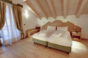 una camera con un grande letto con testiera in legno di Leading Relax Hotel Maria a Moena