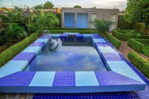 a swimming pool with blue tiles in a yard at Hotel Univers 3 Aeroport Luxe in Niamey