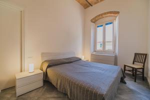 坎普码头Appartamenti Brezza Marina a Campo的一间卧室，里面有一张床、一把椅子和一扇窗户。