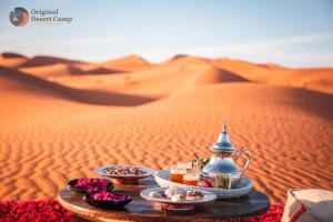 a table in the desert with food and drinks at Original Desert Camp in Merzouga