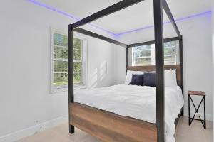 1 dormitorio con cama con dosel, paredes y ventanas blancas en Kaslo Breeze, en Vero Beach