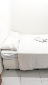 - un lit blanc avec des draps et des oreillers blancs dans l'établissement Blue House, à Baía Formosa