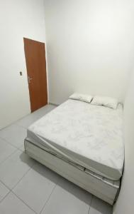 Ce lit se trouve dans un dortoir blanc doté d'un matelas blanc. dans l'établissement Blue House, à Baía Formosa