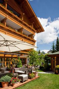 an outdoor patio with couches and an umbrella at Superior Hotel Tirolerhof - Zell am See in Zell am See