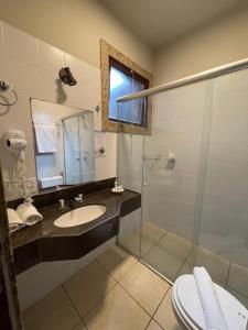 uma casa de banho com um lavatório e uma cabina de duche em vidro. em Hotel Vila Serrana em Sete Lagoas