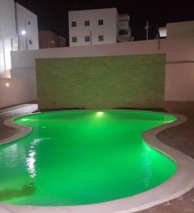 una piscina verde de agua con un edificio al fondo en Reposo Tranquilidad cerca del corazón de Santiago, en Santiago de los Caballeros
