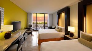 a hotel room with two beds and a television at Paradisus Cancun All Inclusive in Cancún