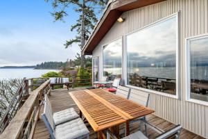 a deck with a wooden table and chairs and a view of the water at The Artists' Beachhouse in Marrowstone