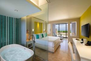 a hotel room with a tub and a bed and a television at Paradisus Cancun All Inclusive in Cancún