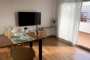 a living room with a table with a television and a table sidx sidx at Precioso Apartamento, luminoso, equipado in Torre de Benagalbón
