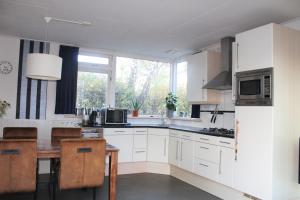 cocina con armarios blancos y ventana grande en Rustig gelegen bungalow op Texel, en Oosterend