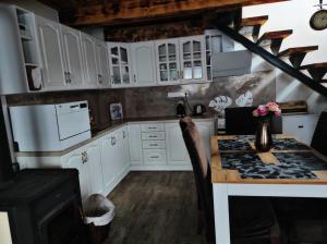 a kitchen with white cabinets and a table with flowers at Apartmán Vladimír - Liptov in Bukovina