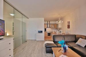 ein Wohnzimmer mit einem braunen Sofa und einer Küche in der Unterkunft Strandresidenz Timmendorfer Strand Strandresidenz Appartement 108 in Timmendorfer Strand