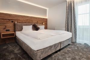 1 dormitorio con 1 cama blanca grande y cabecero de madera en Wieslbauer en Flachau