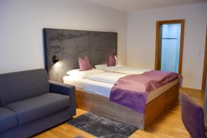 una camera da letto con un letto con una sedia e un divano di Gasthof Ramona a Scharnitz