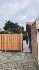 a wooden fence next to a brick building at Slapen bij de Zeeuwse Lala in IJzendijke