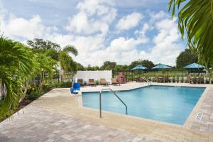 une piscine dans un complexe avec des palmiers et une clôture dans l'établissement Hyatt Place Melbourne - Palm Bay - I-95, à Melbourne