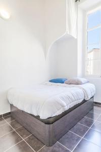 a bed in a bedroom with a white wall at IMMOGROOM - Center - Modern - 10 min from Palais des Festivals in Cannes