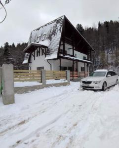 un coche aparcado frente a una casa en la nieve en Mountain Break Azuga, en Azuga