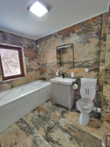 uma casa de banho com um WC, uma banheira e um lavatório. em Mountain Break Azuga em Azuga