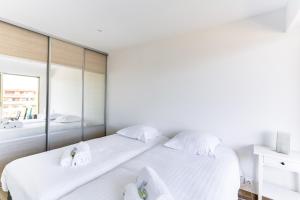 - une chambre blanche avec 2 lits et un miroir dans l'établissement IMMOGROOM - Renovated apartment - Terrace - AC - Wifi, à Cannes