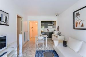 ein Wohnzimmer mit einem weißen Sofa und einer Küche in der Unterkunft IMMOGROOM- Open view terrace - Parking - Next CROISETTE in Cannes