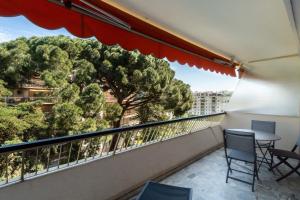 einen Balkon mit einem Tisch, Stühlen und einem Baum in der Unterkunft IMMOGROOM- Open view terrace - Parking - Next CROISETTE in Cannes