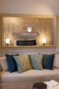 a mirror on the wall above a couch with pillows at Castellano Hotel & Suites in Nafplio