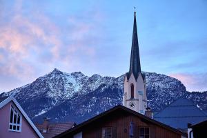 a church with a steeple in front of a mountain at Ferienwohnung Wank in Garmisch-Partenkirchen
