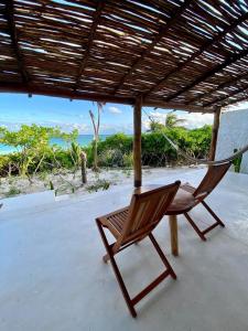 Hotel Poc Na Tulum في تولوم: كرسي جالس على شرفة مطلة على المحيط