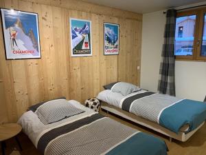 duas camas num quarto com cartazes na parede em CHALET Mitoyen LE RUSTICANA em Chamonix-Mont-Blanc