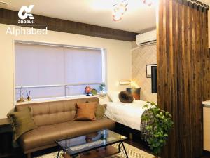 um quarto com um sofá, uma cama e uma janela em Alphabed Takamatsu Furujinmachi - Vacation STAY 11907 em Takamatsu