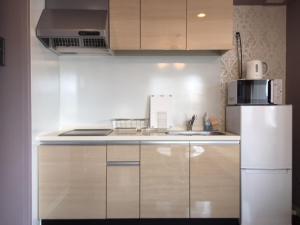 a kitchen with white cabinets and a white refrigerator at Alphabed Takamatsu Furujinmachi - Vacation STAY 11906 in Takamatsu